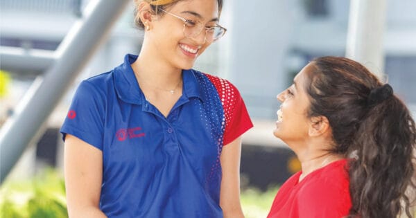 Two smiling women interacting outdoors.
