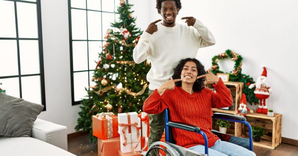 young,interracial,couple,with,woman,sitting,on,wheelchair,by,christmas